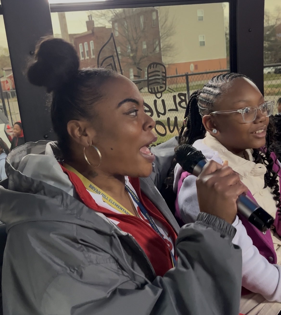 Two women singing passionately, one holding a microphone.